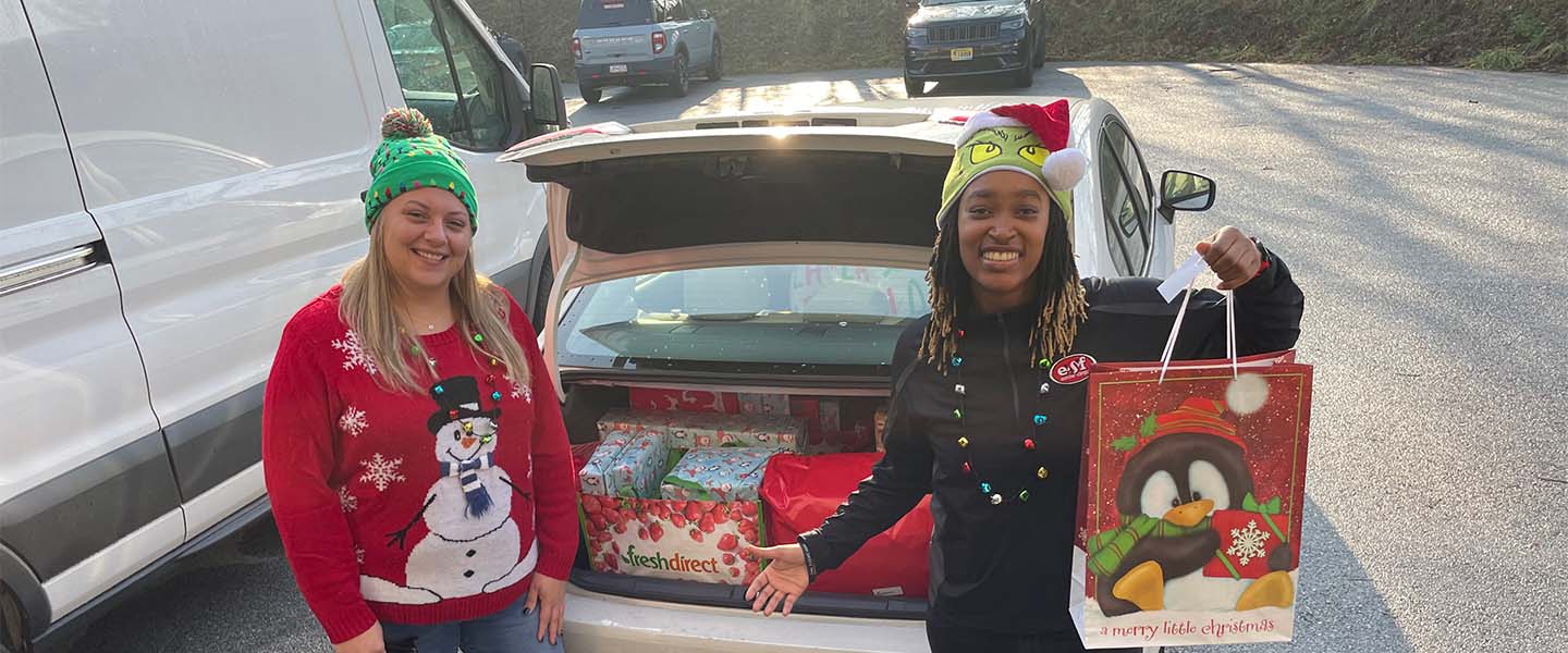 Volunteers putting Christmas gifts in trunk for delivery